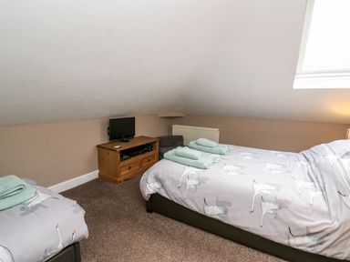A bedroom with two beds a wooden TV stand with a television and a window at Fisher Granary Lampeter