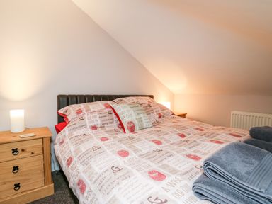 A bedroom with a double bed and wooden bedside tables with lamps at Fisher Granary in Lampeter