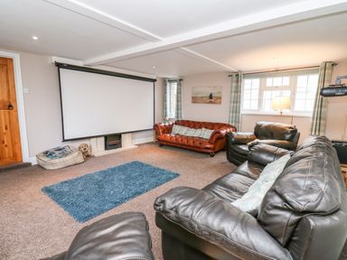 A seating area with leather sofas a projection screen and a blue rug at Fisher Granary in Lampeter