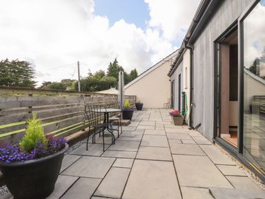 A paved outdoor terrace with metal table and chairs and flower pots at Underfell in Burton-In-Kendal