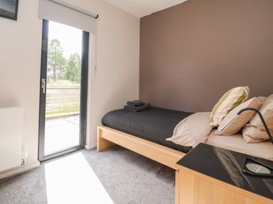 A bedroom with a single bed pillows and folded towels near a glass door at Underfell in Burton-In-Kendal