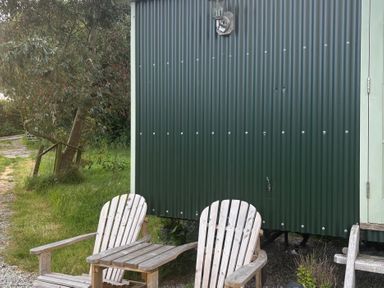 An outdoor area with a shepherd's hut, chairs, and a gravel path at Two Moors Shepherds Hut Hittisleigh