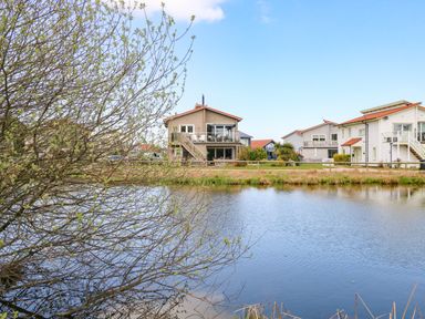 A body of water with houses and trees in the background at Links View in Fritton
