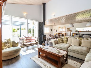 A living room with a beige sofa green pillows wooden coffee table and a fireplace at Links View in Fritton