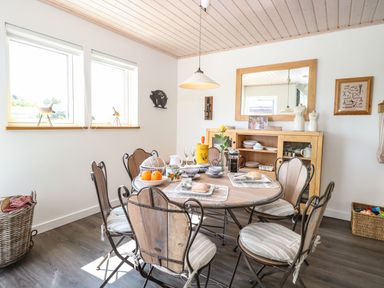 A dining room with a round table set for breakfast and wooden chairs at Links View in Fritton