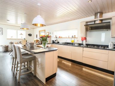 A kitchen with a black countertop island and bar stools at Links View in Fritton