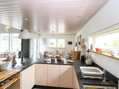 A kitchen with black countertops and white cabinets overlooking a dining area at Links View in Fritton