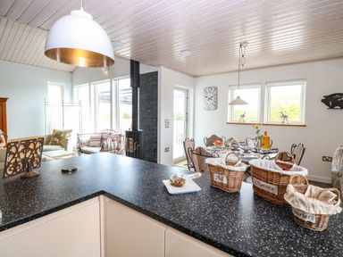 A kitchen and dining area with a black countertop and wicker baskets on the counter at Links View in Fritton