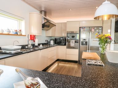 A kitchen with black speckled countertops beige cabinets stainless steel appliances and a vase of flowers on the counter at Links View in Fritton