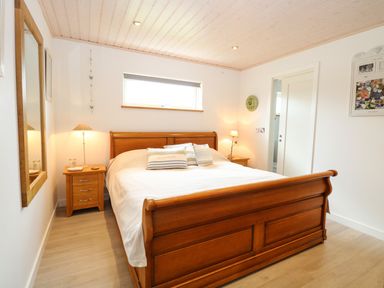 A bedroom with a wooden bed frame and two bedside tables with lamps at Links View in Fritton