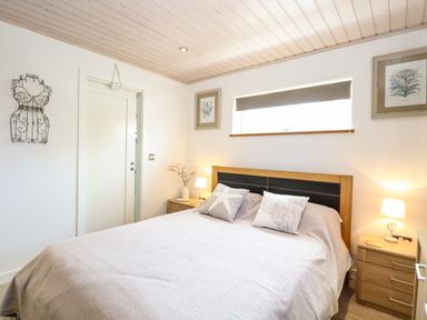 A bedroom with a bed two bedside tables and framed artwork at Links View in Fritton