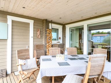 An outdoor covered patio with a dining table and wooden chairs at Links View in Fritton
