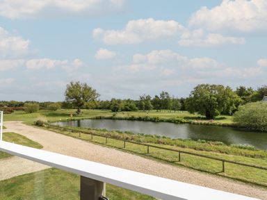 A view of a lake and trees from a balcony at Links View in Fritton