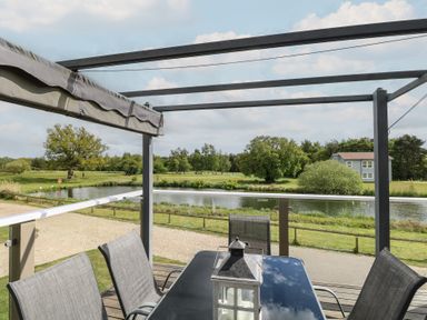 An outdoor area with a table and chairs overlooking a lake at Links View in Fritton