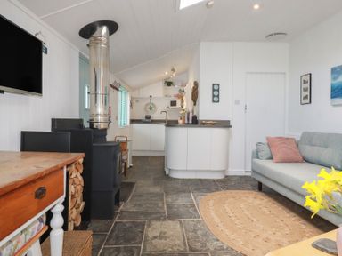 A living room with a stove and sofa at Smugglers Cottage in Trebarwith Strand near Tintagel