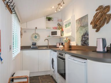 A kitchen with appliances and utensils at Smugglers Cottage Trebarwith Strand near Tintagel