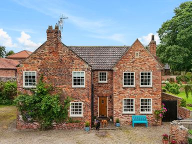 A brick house with multiple windows a wooden door and two dogs standing outside Manor Cottage Northallerton
