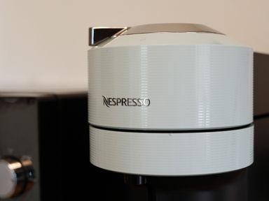 A white Nespresso coffee machine with a silver spout in a kitchen