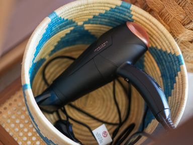 A black hairdryer in a woven basket at Manor Cottage in Northallerton