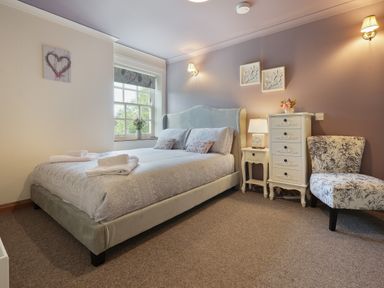 A bedroom with a bed bedside tables chair and window at Manor Cottage in Northallerton
