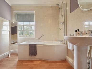 A bathroom with a bathtub shower combination a standing mirror and a sink at Manor Cottage in Northallerton