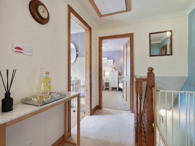 A hallway with a marble table holding bottles and a diffuser next to bathroom and bedroom doors at Manor Cottage in Northallerton