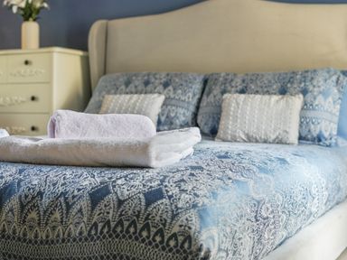 A bed with blue patterned bedding two white pillows and folded towels on top in a bedroom at Manor Cottage in Northallerton