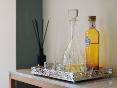 A tray with a decanter bottle, a bottle of ginger liqueur, and several small glasses on a table