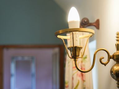 A close up of a brass wall sconce with a light bulb in a room at Manor Cottage in Northallerton