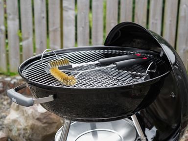 A charcoal grill with cleaning brushes on the grill grate outside in a backyard at Manor Cottage in Northallerton