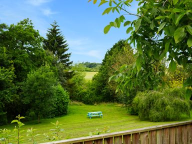 A garden with a blue picnic table surrounded by trees and a wooden fence at Manor Cottage in Northallerton