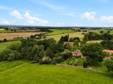 A rural landscape with green fields trees and houses at Manor Cottage in Northallerton