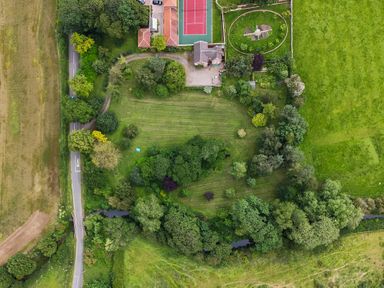 An aerial view of a property with a garden tennis court driveway surrounded by trees and fields at Manor Cottage in Northallerton