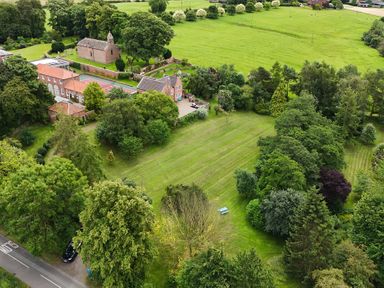 An aerial view of a countryside area with houses trees a road and green fields at Manor Cottage in Northallerton