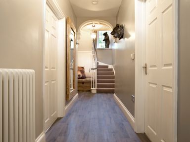 A hallway with wooden flooring white doors and a mirror on the left wall at Penlaurel in Launceston