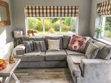 A living room with grey sectional sofa and decorated pillows with bear theme at Penlaurel in Launceston