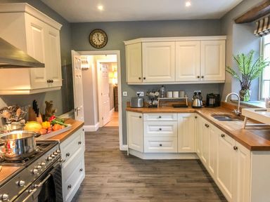 A kitchen with white cabinets wooden countertops and various kitchen appliances at Penlaurel in Launceston