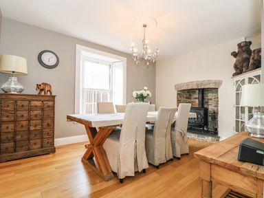 A dining room with wooden table and six chairs a stone fireplace and wooden cabinets at Penlaurel in Launceston