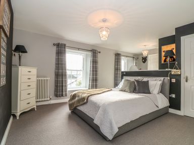 A bedroom with a bed, nightstands with lamps, a dresser, and windows with curtains at Penlaurel in Launceston