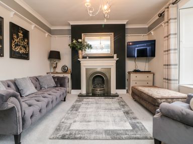A living room with a sofa armchair fireplace mirror and television at Penlaurel in Launceston