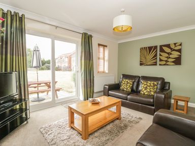 A living room with a brown leather sofa and armchair a wooden coffee table and two wall art pieces at Ladybird in Bridgwater