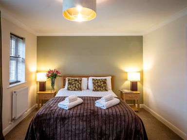 A bedroom with a double bed two bedside tables with lamps and flowers at Ladybird in Bridgwater
