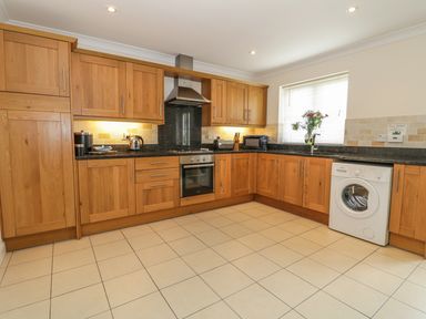 A kitchen with wooden cabinets a washing machine and kitchen appliances at Dragonfly in Bridgwater