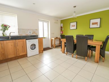 A kitchen and dining area with a wooden dining table and black chairs at Dragonfly in Bridgwater
