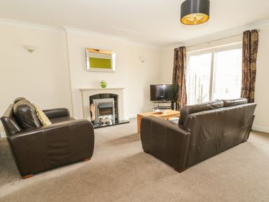 A living room with two brown leather sofas a fireplace a wall mirror a wooden coffee table and a television at Dragonfly in Bridgwater