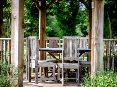 A wooden outdoor seating area with a round table and six wooden chairs in a garden at Dragonfly Bridgwater