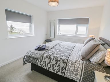 A bedroom with a double bed two windows and bedside lamps at Hendre Wylan in Llanaber