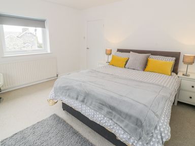 A bedroom with a bed with pillows and bedside tables with lamps at Hendre Wylan in Llanaber