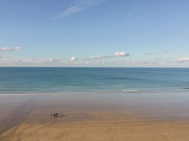 A beach with a group of people walking near the water at Onshore 6 - Newquay Towan Beach View in Newquay