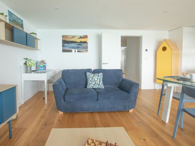 A living room with a blue sofa table and chair shelves and a yellow cabinet at Onshore 6 - Newquay Towan Beach View in Newquay